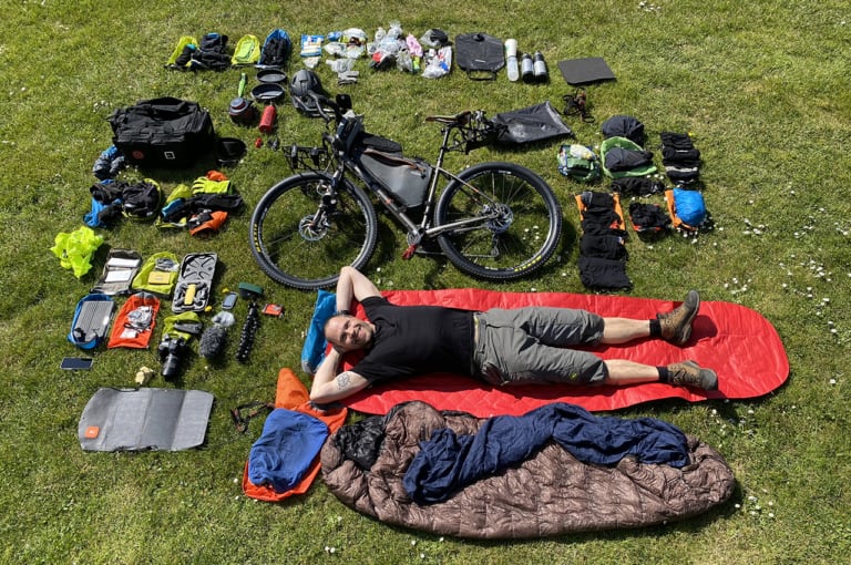 Erik B. Jørgensen ligger med alt hans grej og bikepackingcykel rundt om sig, før Bikepacking, Danmark rundt