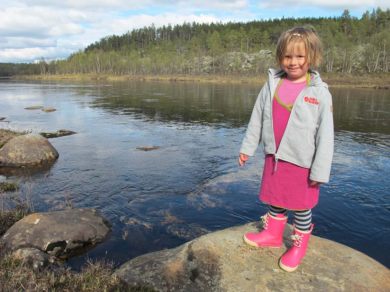Karen 3 år, står ved en lille flod, Ivalo, i Finland,