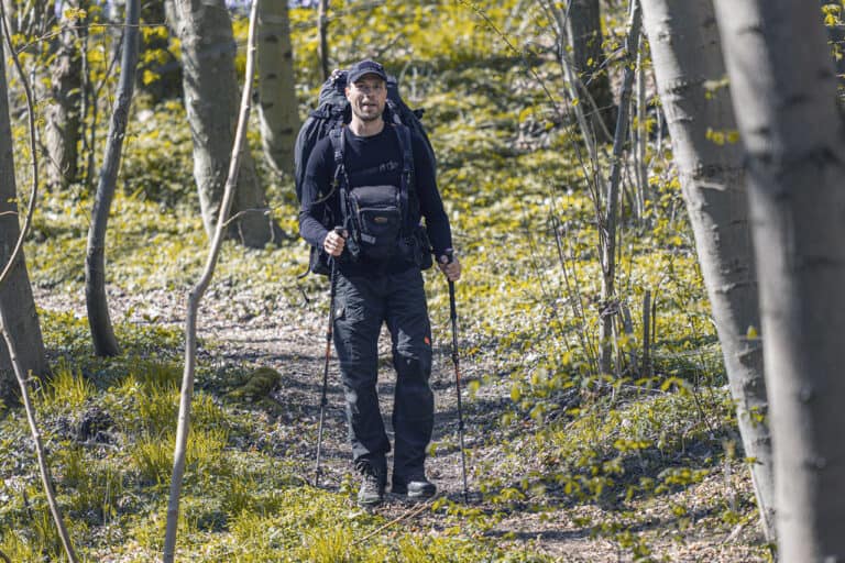 Billede af Erik B. Jørgensen, der vandre i skoven med rygsæk, fototaske og vandrestave. Foto Claus Lillevang