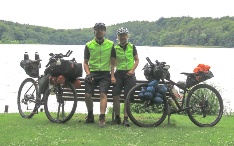 Erik B. Jørgensen og Tine Henriksen, står ved bænk, med deres bikepackingcykler, under Bikepacking, Danmark rundt