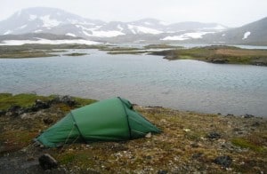 Telt anmeldelse af Hilleberg telt, Nallo 2. Billede af teltet på fjeldet, ved sø og bjerge med sne i baggrunden. Grønland.